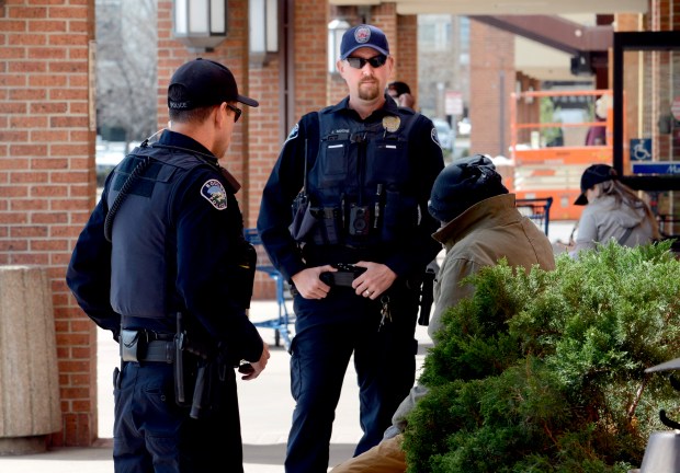 Boulder police officers, A. Stiso, left, and Jared Moore, make a welfare check on a man outside a store in Boulder in April. (Cliff Grassmick ??